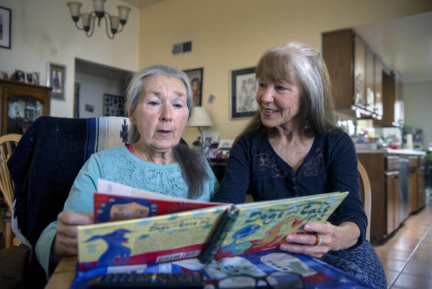em022819c/jnorth/Susan Goseyun, right, reads with her sister Jane Morrison at their home in Santa Fe, Thursday February 28, 2019. Goseyun takes care of Morrison, who suffers from memory loss, 24 hours a day. (Eddie Moore/Albuquerque Journal)